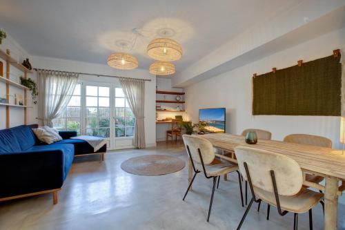 a living room with a table and a blue couch at Casa Golden Bamboo, private patio & 100m from the river! in Vila Nova de Milfontes