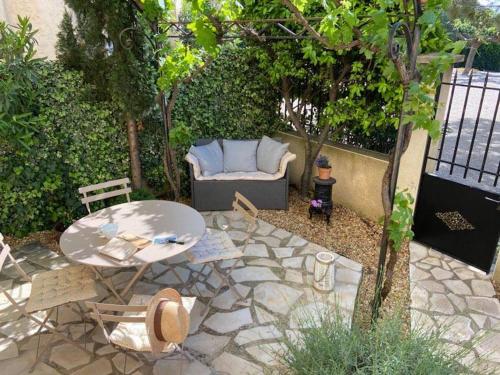 a patio with a table and a couch and a table and chairs at Le Petit Jardin in Sablet