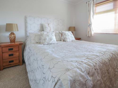 a bedroom with a white bed and a window at Elm Lodge in Longhope