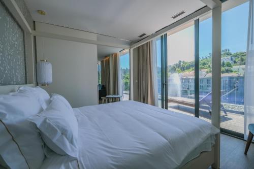 um quarto com uma cama branca e uma grande janela em Hotel Vouga nas Termas de São Pedro do Sul