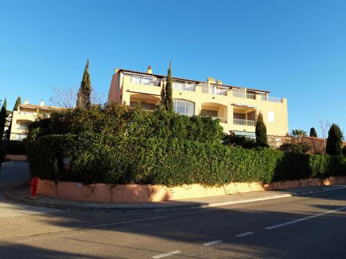 un bâtiment avec des buissons en face d'une rue dans l'établissement T2, jardin, véranda chambre, climatisation, parking privatif, proche à pied centre, plage, gare, pour 3 adultes ou 2 adultes avec 2 enfants, à Bandol