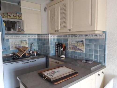 une cuisine avec des placards blancs et du carrelage bleu dans l'établissement T2, jardin, véranda chambre, climatisation, parking privatif, proche à pied centre, plage, gare, pour 3 adultes ou 2 adultes avec 2 enfants, à Bandol