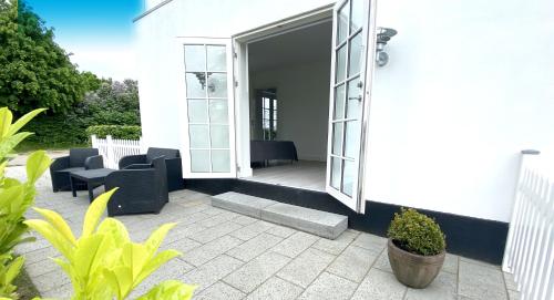 a white house with a patio with chairs and tables at The Beach House Suite in Karlslunde