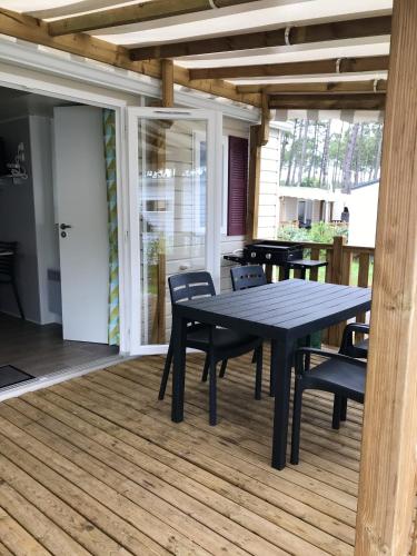 une table et des chaises noires sur une terrasse avec une table et des chaises dans l'établissement Bungalow confortable à Saint-Julien-en-Born avec piscine partagée, à Saint-Julien-en-Born