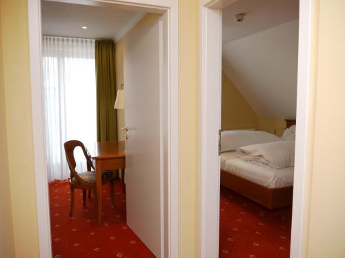 a bedroom with a bed and a table with a chair at Hotel Thomahof in Hinterzarten