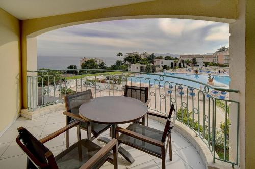 d'un balcon avec une table, des chaises et une piscine. dans l'établissement IMMOGROOM - 2 Rooms sea view - Swimming pool - Terrace - Parking - AC, à Cannes