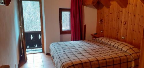 um quarto com uma cama e uma janela com cortinas vermelhas em Hotel Cristallo em Macugnaga