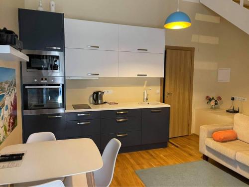 a kitchen with white cabinets and a table and a couch at Kuninga Old Town Resident in Pärnu