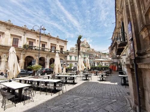 an outdoor patio with tables and umbrellas on a city street at Casa Concetta in Modica