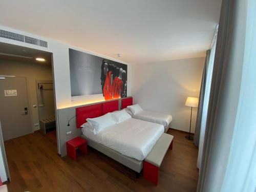 a bedroom with a bed with white sheets and red accents at Amedia Hotel Milan, Trademark Collection by Wyndham in Milan