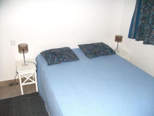 une chambre avec un lit bleu avec deux oreillers dessus dans l'établissement Beau 2 pièces avec vue mer en terrasse face plage de Gigaro, à La Croix-Valmer