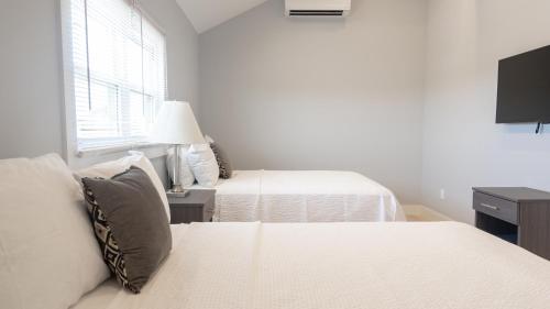 a white bedroom with two beds and a window at A Wave Inn - Montauk in Montauk