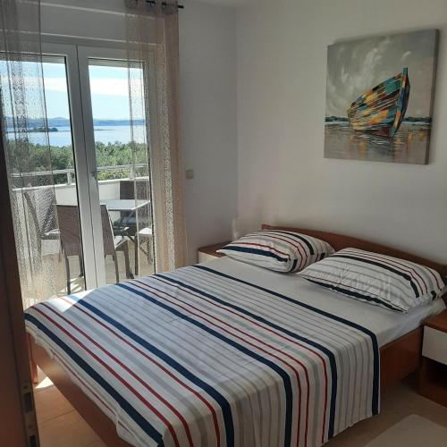 a bed with a striped blanket in a room with a window at APARTMAN KAVALA in Kraj