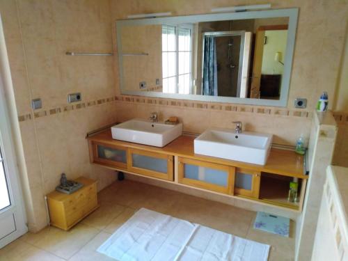 een badkamer met 2 wastafels en een grote spiegel bij Estrella Del Mar Tranquil and spacious villa, convenient location 3-5 mins' walk to all amenities in Villacosta