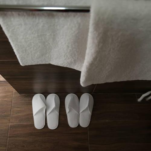 two white shoes on the floor next to a towel at Apartments & Dream Rooms in Niš