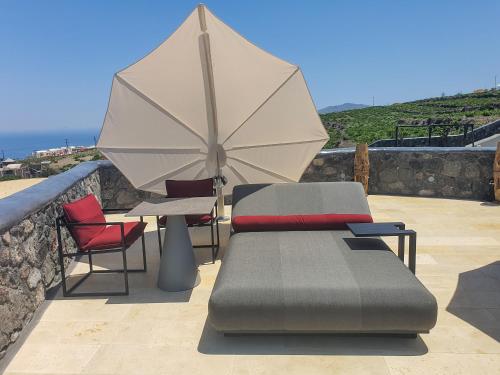 a table and chairs with an umbrella on a patio at White Pearl Cavalieri in Imerovigli