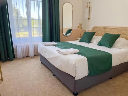 a bedroom with a large bed with green and white sheets at Grand Hôtel Saint-Aignan in Saint-Aignan