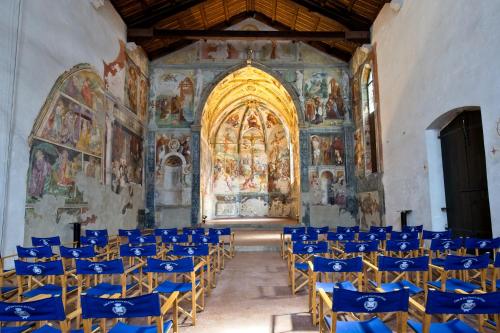 a church with blue chairs and paintings on the walls at Delma's home in San Daniele del Friuli