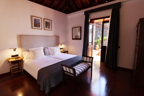 a bedroom with a large white bed and a chair at Hotel Escuela Rural Casa Los Herrera in Hermigua