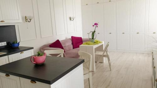 une cuisine blanche avec un canapé rose et une table dans l'établissement Luxury Apartments Alix, à Bourgas