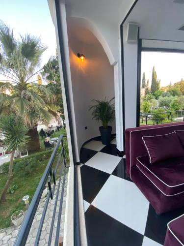 a balcony with a couch and a palm tree at Garden Boutique Hotel in Elbasan