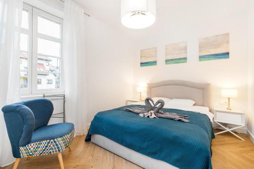 sypialnia z łóżkiem i niebieskim krzesłem w obiekcie Holiday Sopot Apartment w mieście Sopot