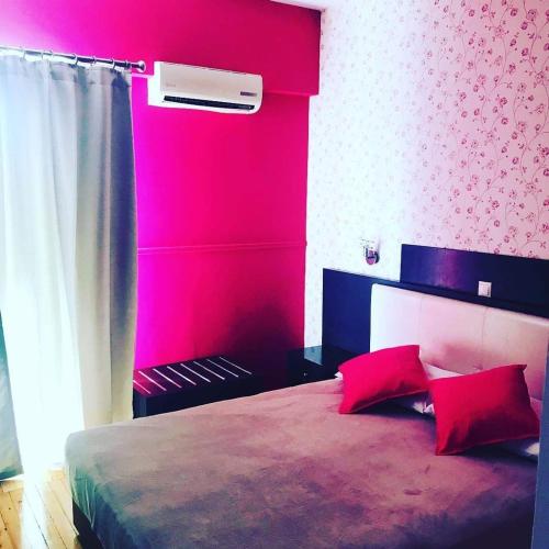 een slaapkamer met een bed met een roze muur bij Aegean Sea Rooms in Chios