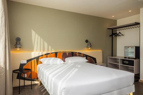 a bedroom with a large white bed and a television at Ibis Styles Lisboa Centro Liberdade NE in Lisbon