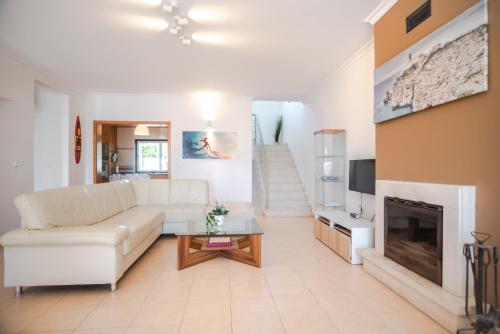 a living room with a white couch and a fireplace at Kichershome in Sagres