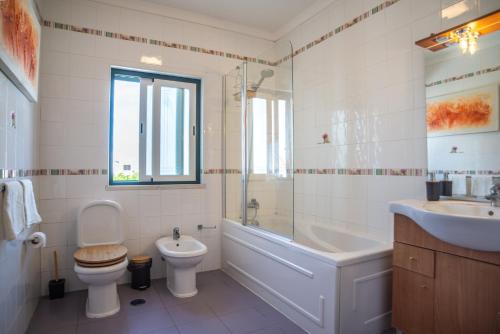 uma casa de banho com um WC, uma banheira e um lavatório. em Kichershome em Sagres
