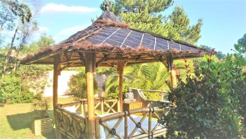 a wooden gazebo with a thatched roof at Hotel Les Jardins de Bormes in Bormes-les-Mimosas