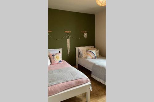 two beds in a bedroom with green walls at Mary-Jane’s Cottage in Omagh