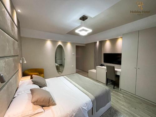 a bedroom with a large bed and a desk at Hotel Holiday in Podgorica