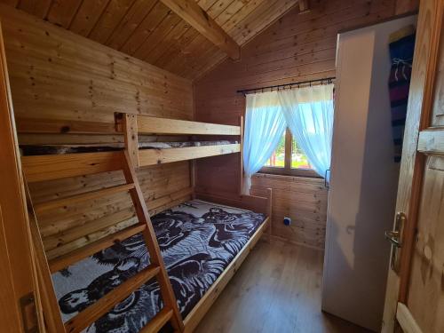 a bedroom with bunk beds in a log cabin at Domki letniskowe Zacisze in Rusinowo