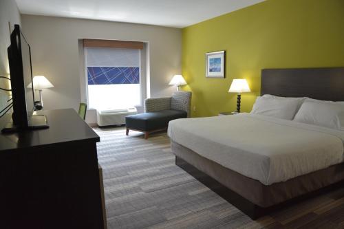 a hotel room with a bed and a chair at Holiday Inn Express & Suites Caryville by IHG in Caryville