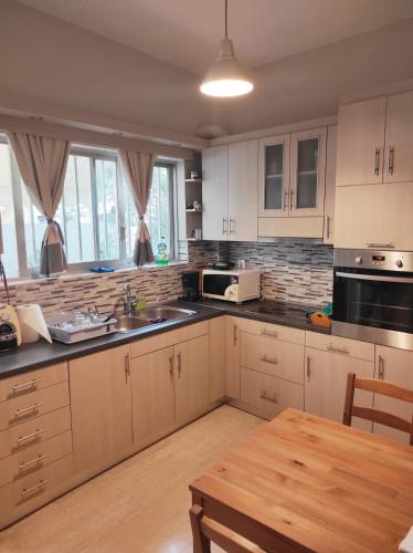 cocina con armarios blancos y mesa de madera en Alimos Apartment en Athens