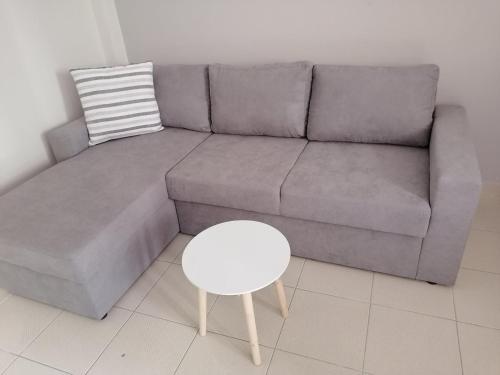un sofá gris con un taburete blanco y una mesa en Nicole Apartment, en Perdika
