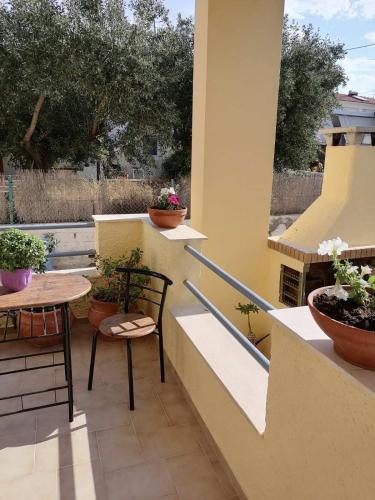 a balcony with a table and chairs and potted plants at Nicole Apartment in Perdhika