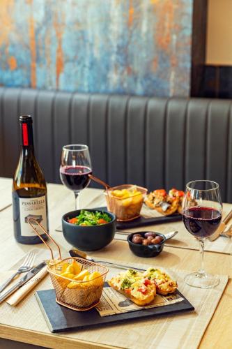 a table with glasses of wine and food on it at Ibis Styles Lisboa Centro Liberdade NE in Lisbon