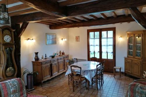 une cuisine avec une table, des chaises et une horloge dans l'établissement Maison entière la longe'yeres, à Saint-Martin-le-Gaillard