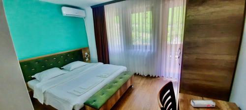 a bedroom with a large bed with a green headboard at Vila Alexander B&B in Valbonë