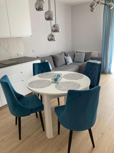 科沃布熱格的住宿－Apartament Azzurro Porta Mare Baltica Kołobrzeg，客厅配有带蓝色椅子的白色桌子