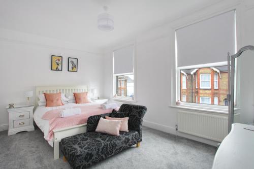 ein Schlafzimmer mit einem Bett und einem Stuhl und Fenstern in der Unterkunft Sea Salt Cottage - Mins to beach & shops Dog Friendly in Deal