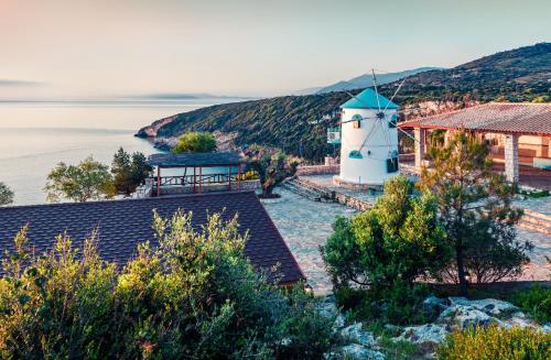 a lighthouse on a hill next to a body of water at Potamitis Windmills & Apartments - Unique Stay with Scenic Views, by ZanteWize in Koríthion