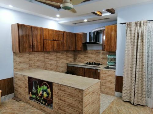 uma cozinha com armários de madeira e uma bancada em Full Private House Floor with Lounge & Balcony - Townhouse - Homestay em Lahore