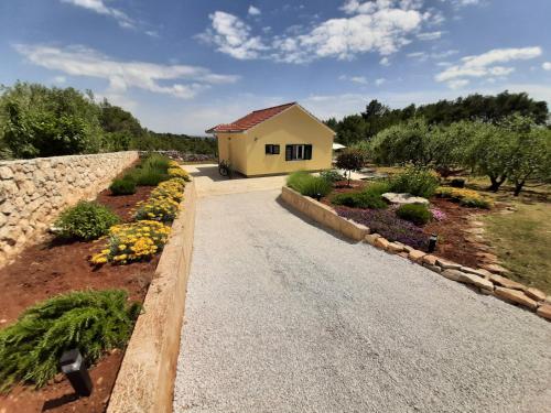 eine Straße, die zu einem gelben Haus mit Blumen führt in der Unterkunft Happy garden house in Kožino