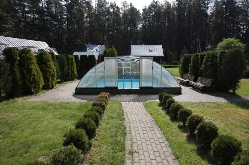 a glass house in the middle of a garden at Sigito sodyba in Jaskonys