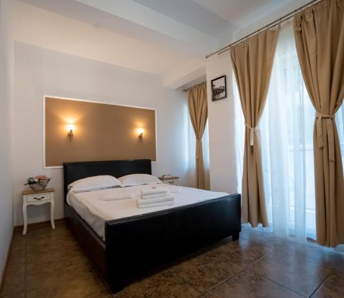 a bedroom with a bed with a black headboard and curtains at Vila 27 in Eforie Nord