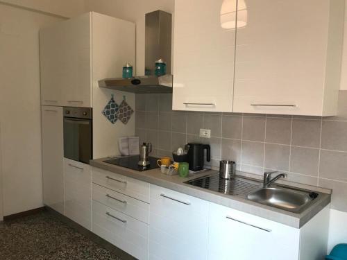 eine Küche mit weißen Schränken und einem Waschbecken in der Unterkunft Le case di Sara n 6 in Savona