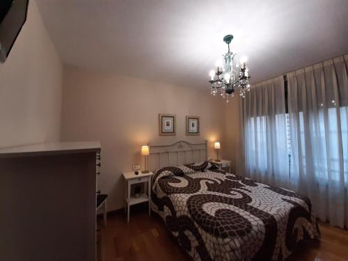 1 dormitorio con cama y lámpara de araña en PUERTO DEPORTIVO CENTRO wifi en Gijón